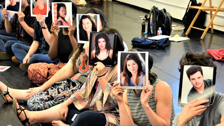 Students hold their head shots in front of their faces