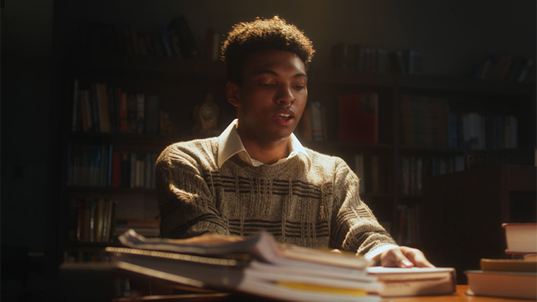 Student surrounded by books studies late at night