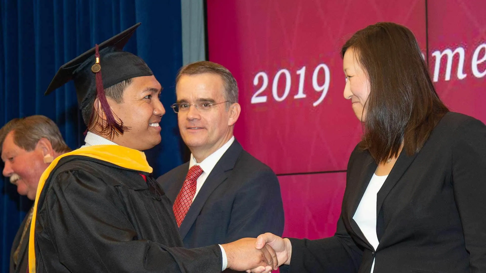 Graduate shakes hands with professors